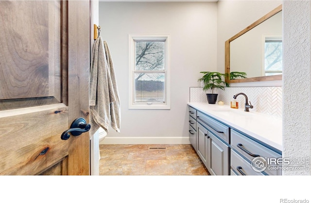 bathroom with toilet, vanity, and decorative backsplash