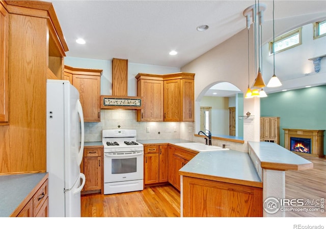 kitchen featuring white appliances, kitchen peninsula, custom exhaust hood, hanging light fixtures, and sink