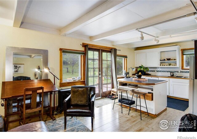 interior space with beam ceiling, french doors, and light hardwood / wood-style floors