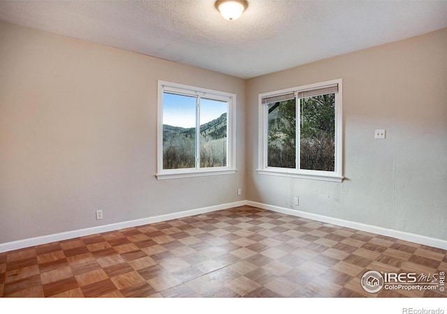 unfurnished room with a textured ceiling and a mountain view