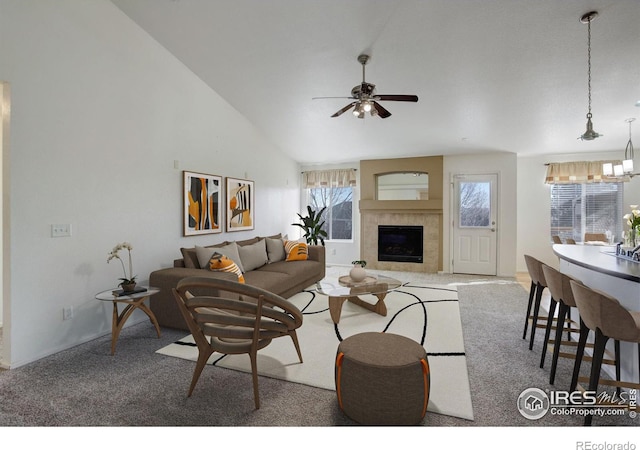 living room featuring ceiling fan with notable chandelier, a tile fireplace, high vaulted ceiling, and carpet