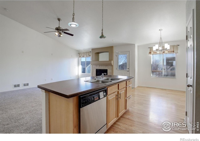 kitchen featuring an island with sink, light brown cabinets, hanging light fixtures, stainless steel dishwasher, and sink