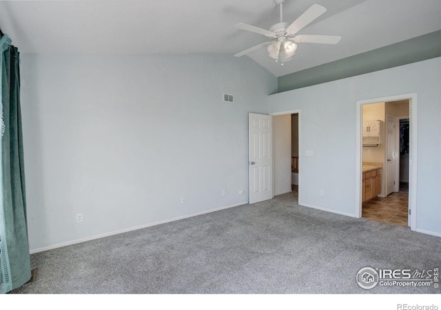 unfurnished bedroom featuring ceiling fan, ensuite bath, light colored carpet, and high vaulted ceiling