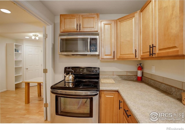 kitchen with light brown cabinetry, appliances with stainless steel finishes, and light hardwood / wood-style flooring