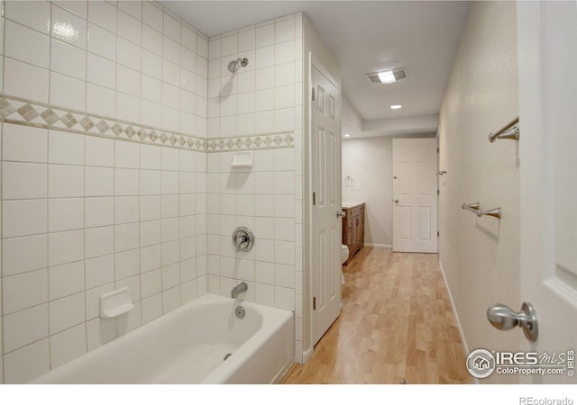 bathroom featuring hardwood / wood-style flooring, vanity, and tiled shower / bath