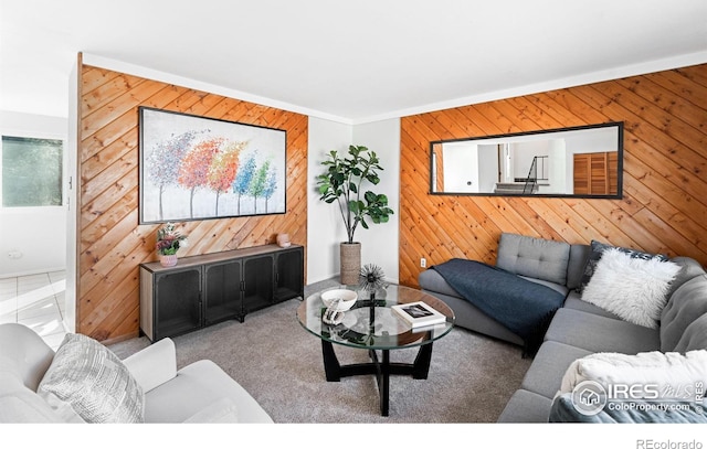 carpeted living room with wood walls and ornamental molding