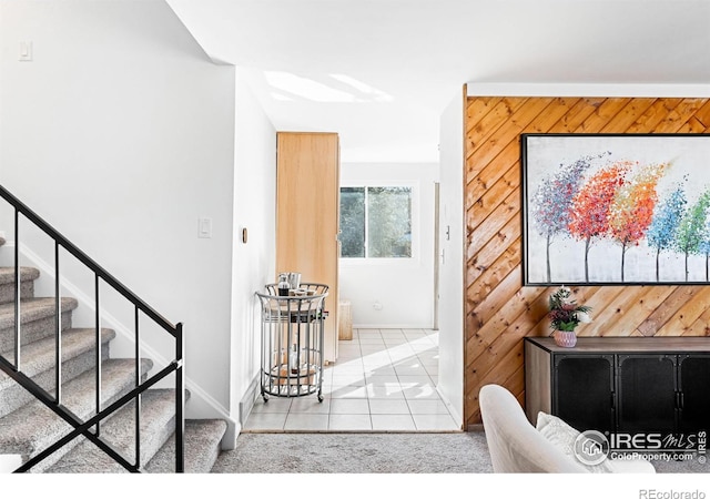 doorway featuring light tile patterned flooring and wooden walls