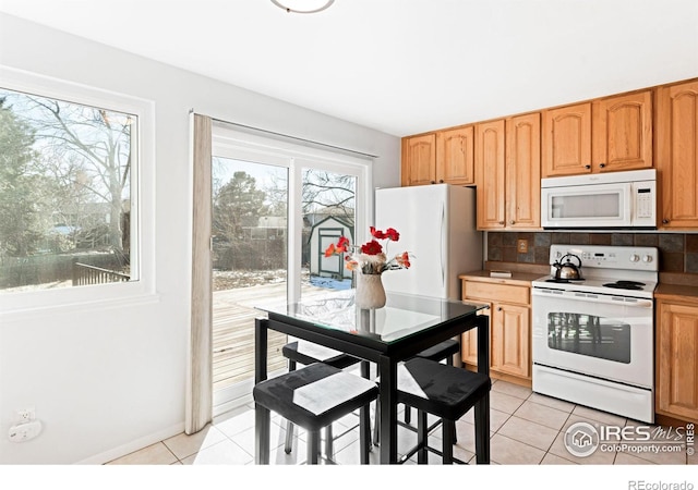 kitchen with white appliances, decorative backsplash, a healthy amount of sunlight, and light tile patterned floors