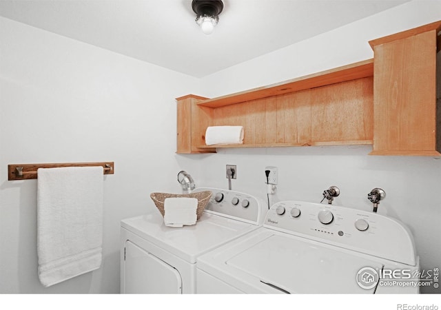 laundry room featuring washing machine and clothes dryer and cabinets