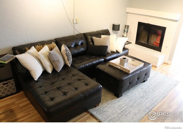 living room with a brick fireplace and hardwood / wood-style floors