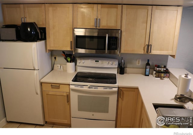 kitchen with white appliances, sink, and light brown cabinets