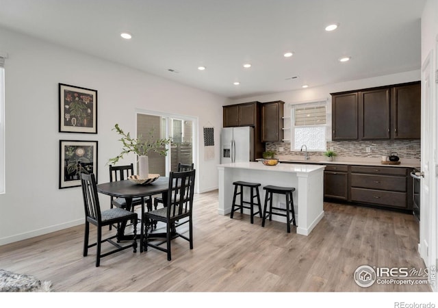 kitchen with a center island, stainless steel fridge with ice dispenser, a breakfast bar, light hardwood / wood-style floors, and sink