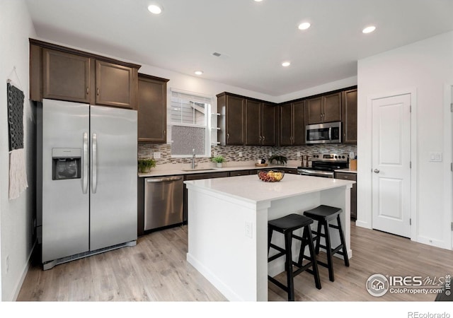 kitchen featuring a center island, light hardwood / wood-style floors, dark brown cabinetry, appliances with stainless steel finishes, and sink