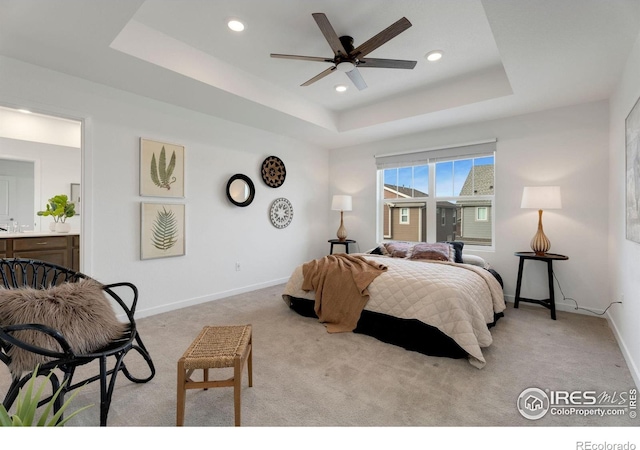 bedroom featuring ceiling fan, light carpet, and a raised ceiling