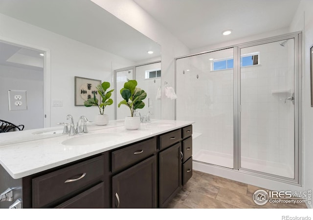 bathroom featuring a shower with door and vanity