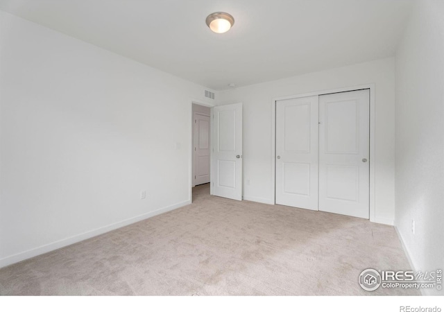 unfurnished bedroom featuring light colored carpet and a closet