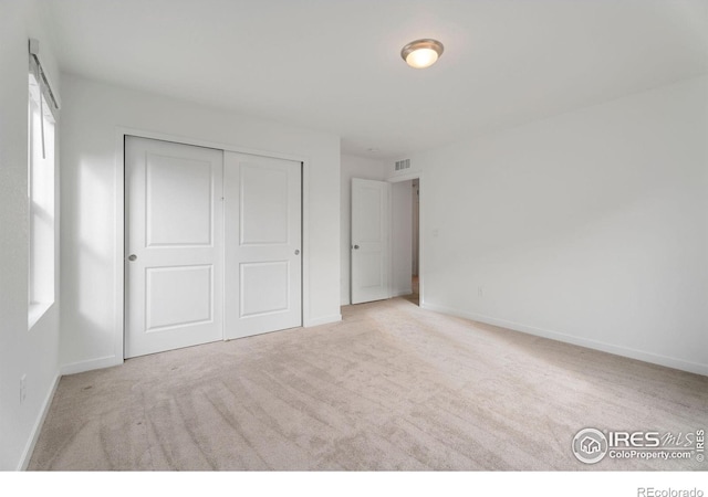 unfurnished bedroom with a closet and light carpet