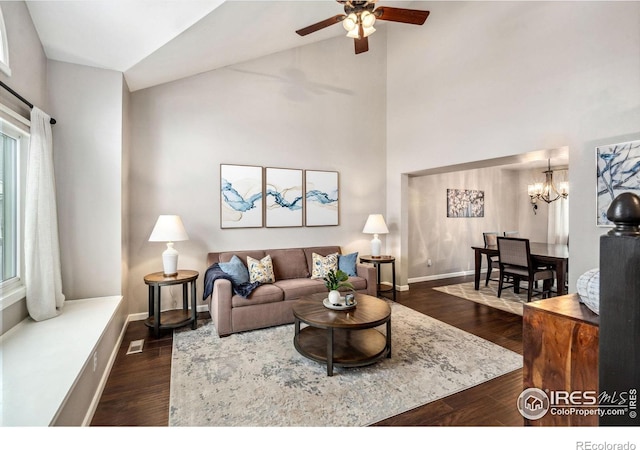 living room with dark hardwood / wood-style flooring, vaulted ceiling, and ceiling fan with notable chandelier