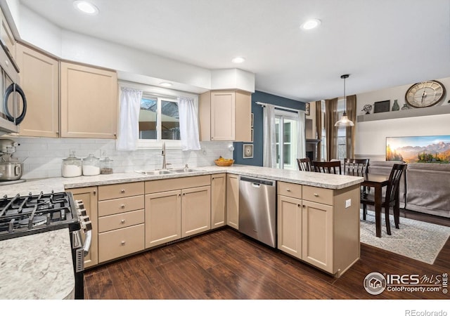 kitchen featuring sink, kitchen peninsula, hanging light fixtures, dark hardwood / wood-style floors, and appliances with stainless steel finishes