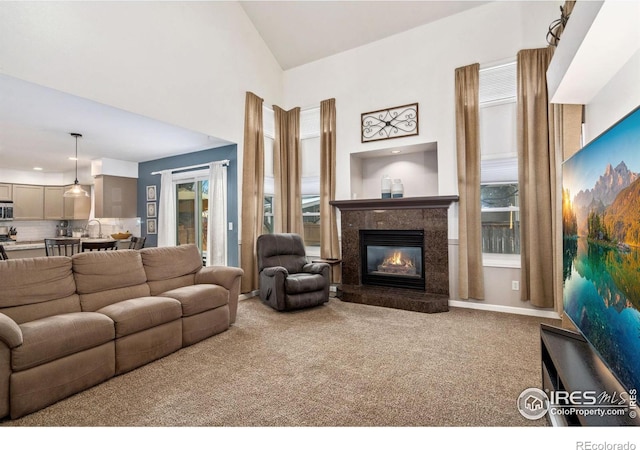 living room featuring sink, a premium fireplace, carpet floors, and a healthy amount of sunlight