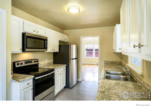 kitchen featuring sink, stainless steel appliances, white cabinetry, and light stone counters