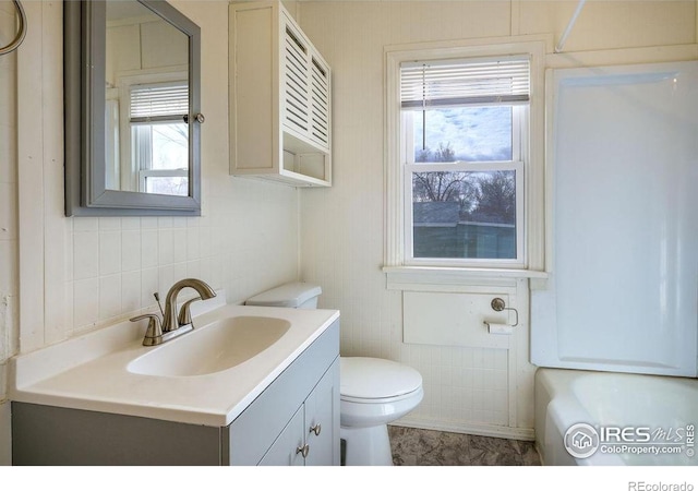 bathroom featuring toilet, vanity, and a wealth of natural light