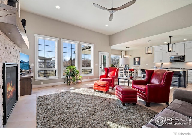 living room featuring ceiling fan, plenty of natural light, and a fireplace