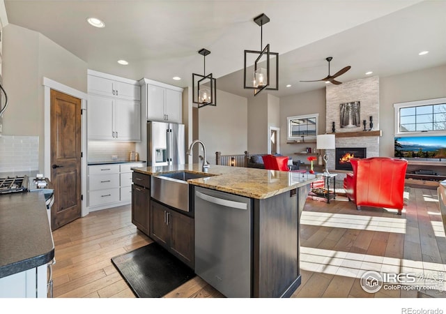 kitchen featuring appliances with stainless steel finishes, white cabinetry, decorative backsplash, and an island with sink