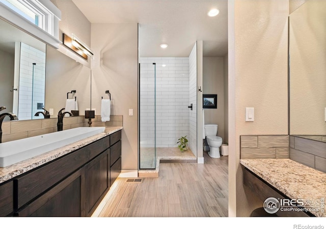 bathroom with a tile shower, vanity, and toilet