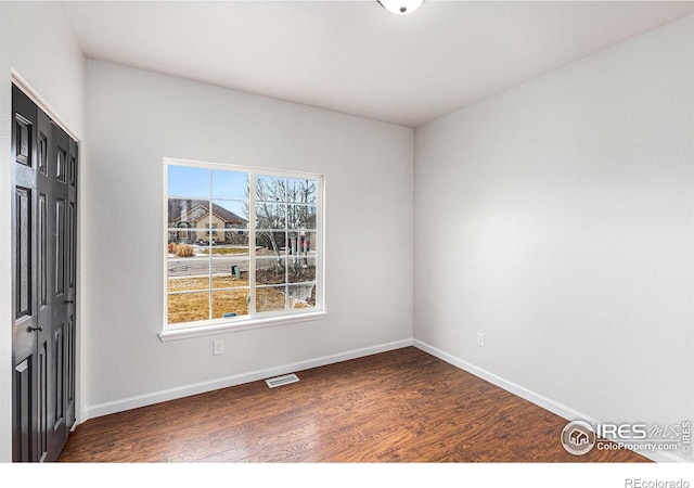 unfurnished room with wood finished floors, visible vents, and baseboards