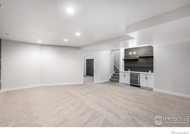 unfurnished living room featuring stairway, beverage cooler, recessed lighting, a dry bar, and light colored carpet