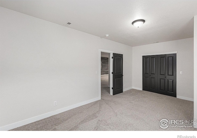 unfurnished bedroom featuring a closet, visible vents, baseboards, and carpet floors