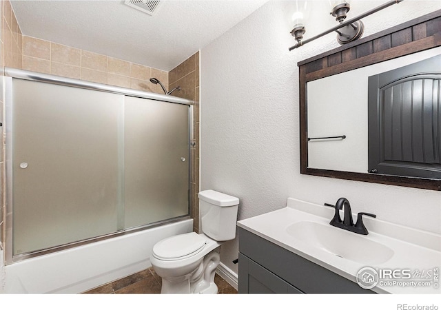 full bath with vanity, visible vents, a textured ceiling, toilet, and combined bath / shower with glass door