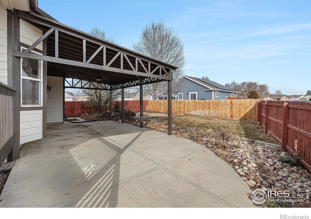 view of patio / terrace featuring a carport, a fenced backyard, and driveway