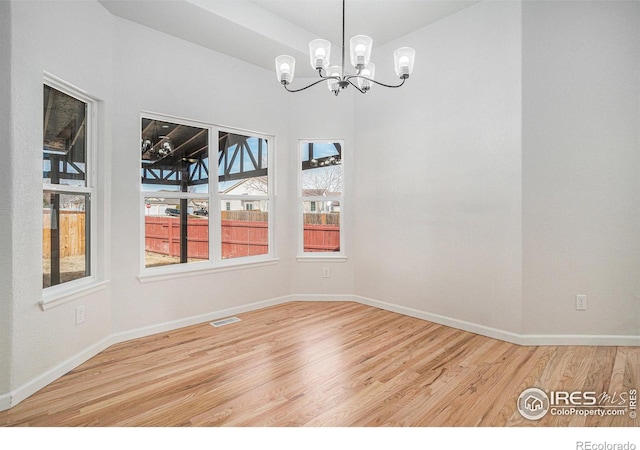 unfurnished dining area featuring a chandelier, visible vents, baseboards, and wood finished floors