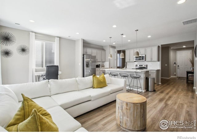 living room with sink and light hardwood / wood-style flooring