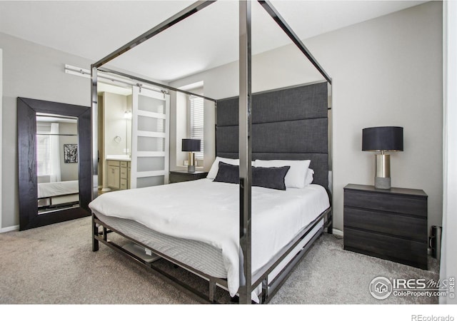 bedroom with ensuite bath and light colored carpet