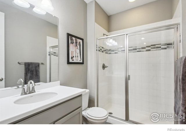 bathroom with toilet, a shower with door, and vanity