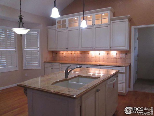 kitchen with sink, white cabinets, a kitchen island with sink, and decorative light fixtures