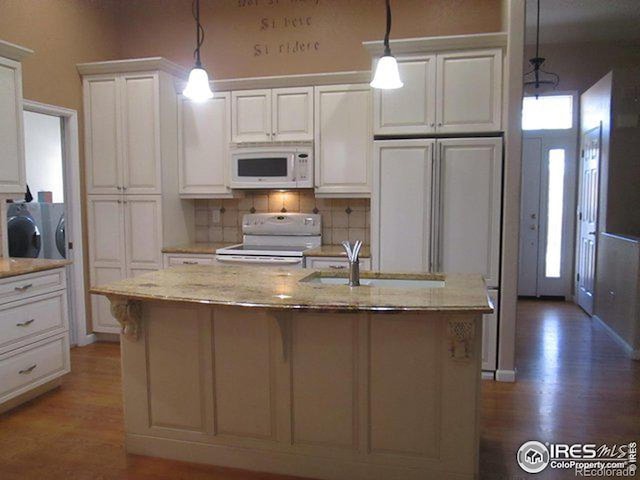 kitchen featuring white appliances, white cabinetry, and decorative light fixtures