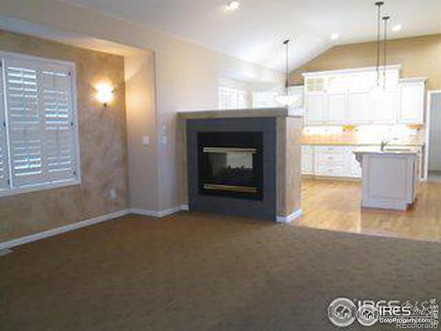 kitchen featuring hanging light fixtures, white cabinetry, a center island, and lofted ceiling