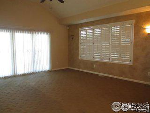 carpeted empty room with ceiling fan and lofted ceiling