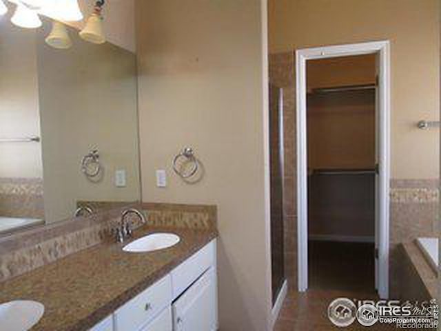 bathroom featuring tiled tub and vanity