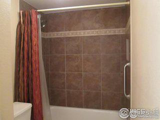 bathroom with toilet and shower / bathtub combination with curtain