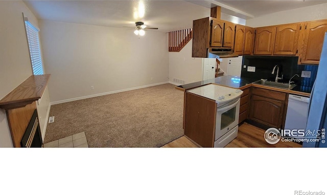 kitchen featuring white appliances, carpet, ceiling fan, sink, and backsplash