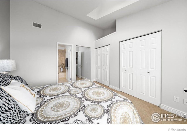 bedroom featuring a high ceiling, a skylight, and multiple closets