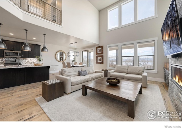 living room featuring a high ceiling, light hardwood / wood-style flooring, sink, and a fireplace