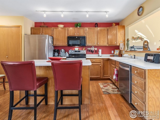 kitchen featuring a kitchen bar, sink, light hardwood / wood-style flooring, and stainless steel appliances