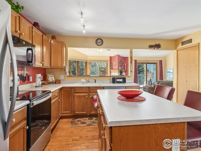 kitchen with stainless steel appliances, track lighting, a kitchen island, and sink