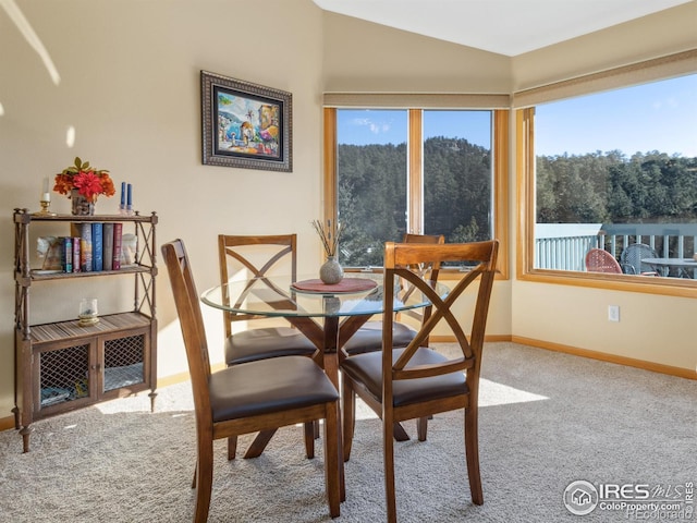 carpeted dining space featuring vaulted ceiling